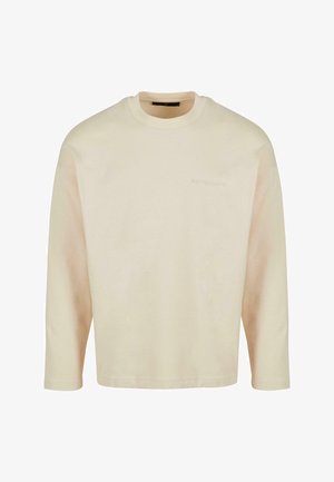 Cream long-sleeve t-shirt made of soft cotton. Features a round neckline and loose fit, with subtle embossed branding on the chest.