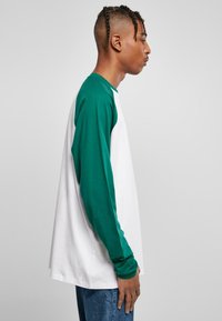 Langarmshirt mit grünen Ärmeln und weißem Körper, aus weichem Baumwollmaterial, mit Rundhalsausschnitt und lässiger Passform.