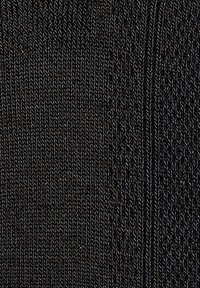 Schwarzer Strickstoff mit einem strukturierten Muster und diagonalen Rippen. Glatte Textur mit gleichmäßigen Nähten.