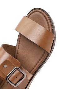 Brown leather sandal with two wide straps, a metal buckle, and a textured insole. Features a durable rubber outsole and stitching accents.