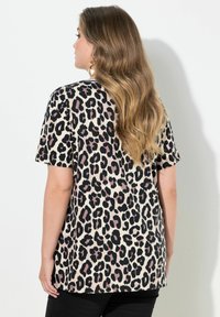 Camisa de manga corta con estampado de leopardo en beige con manchas negras y malva, que presenta un ajuste holgado y una textura suave.