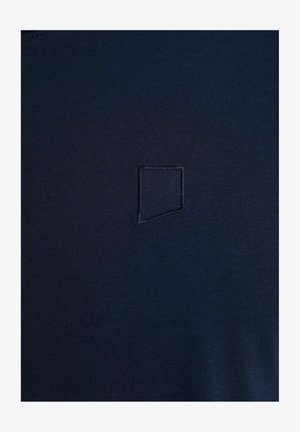 Mörkblå t-shirt i slät tyg med en liten, broderad fyrkantig logotyp på bröstet.