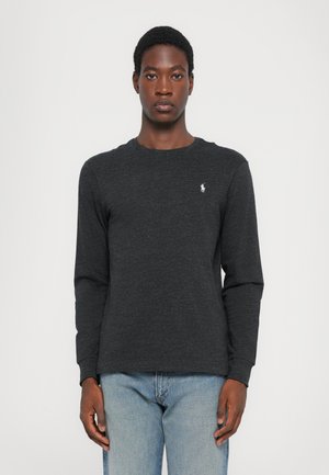 Donkergrauw t-shirt met lange mouwen van zachte stof, met een ronde halslijn, voorzien van een klein wit geborduurd logo op de linkerborst.