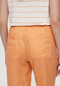 Lichte, oranje linnen broeken met een ontspannen pasvorm, elastische tailleband en twee achterzakken met zichtbare stikdetails.