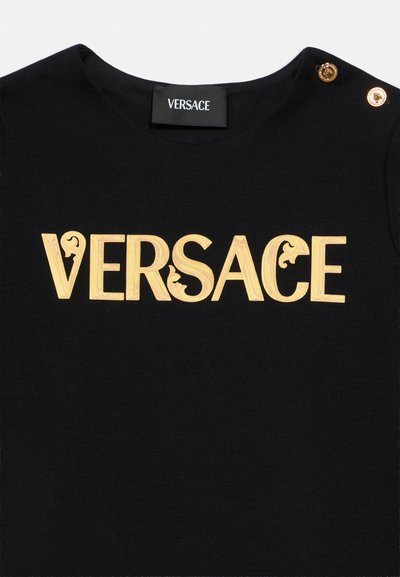 Czarna bawełniana koszulka z dużym złotym logo "VERSACE". Złote ozdobne guziki na ramieniu. Gładka faktura.