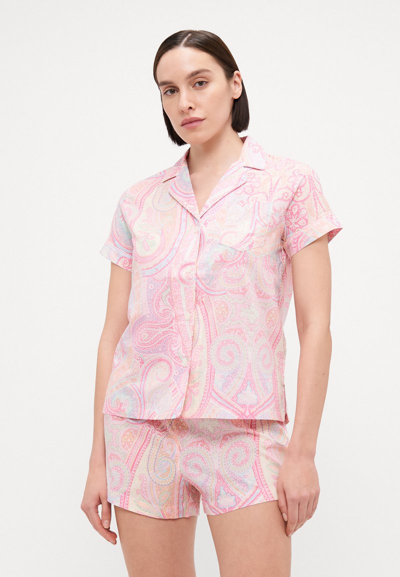 Conjunto de pijama ligero en rosa pastel con un patrón de paisley. La parte superior de manga corta cuenta con un cierre de botones y un bolsillo en el pecho; los pantalones cortos tienen una cintura elástica.