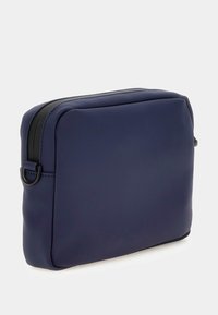 Bolso rectangular de color azul marino, fabricado en material suave, con un zipper negro y tiradores redondos, con un diseño plano y minimalista.