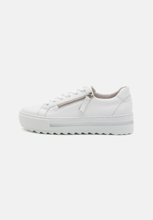 Sneaker in pelle bianca con punta tondeggiante, dettaglio con zip sul lato e suola bianca testurizzata con motivo a zigzag.