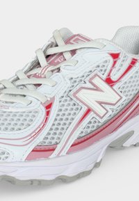 Λευκό και ροζ αθλητικό παπούτσι New Balance με πλέγμα ανώτερο μέρος, δέσιμο με κορδόνια και χοντρή καουτσούκ σόλα.