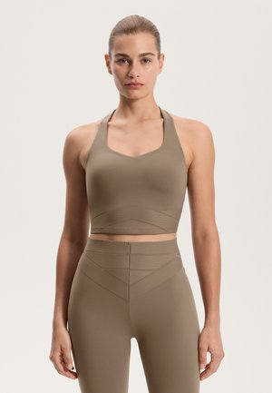 Bruine crop top met een V-hals en brede bandjes; heeft textuuraccentlijnen. Gecombineerd met bijpassende high-waisted legging.