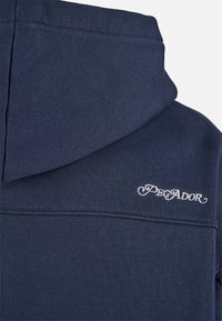 Navy blue hoodie featuring a textured fabric, a large hood, and embroidered "Pegador" logo in white on the upper left side.