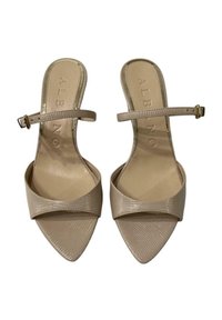 Sandali beige con tacco, punta affusolata, finitura lucida e design incrociato sulla parte superiore. Cinturino alla caviglia regolabile con dettagli in oro.