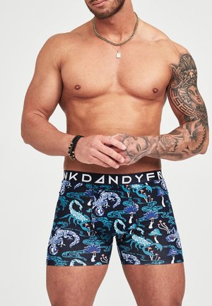 Boxerit farkkujen vyötäröllä, jossa on musta vyö ja "Dandy"-teksti, koristeltuna värikkäillä vesieliö- ja skorpioni kuvioilla tummalla taustalla.