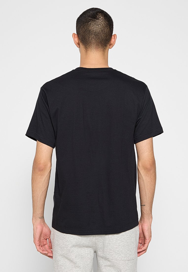 Camiseta de algodón negra con un cuello redondo estándar y mangas cortas. Textura suave, diseño simple sin gráficos ni patrones.