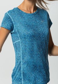 Blå idrottströja med en strukturerad mönster, korta ärmar och en figursydd design. Inkluderar en liten logotyp på bröstet.