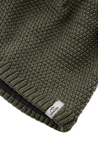 Knit green beanie with textured surface, ribbed hem, and a white label featuring a logo. The interior is black and smooth.