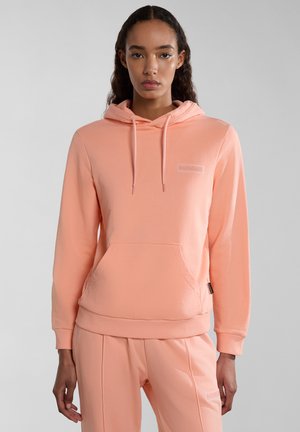 Perzikkleurige hoodie gemaakt van zacht materiaal, met een kangoeroezak, ribgebreide mouwen en een logo-embleem op de borst. Soepele textuur.