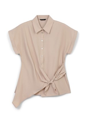 Chemise beige clair à manches courtes avec un col pointu, fermeture à boutons, et un ourlet asymétrique noué sur le côté. Tissu souple et léger.