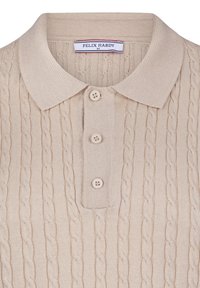 Camisa polo de algodón beige con una textura de punto de cable, tapeta de botones con tres botones y un cuello clásico. Etiqueta de la marca visible.