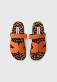 Narančaste sandale s izrezbarenom dizajnom i dvije podesive trake. Insole s leopard uzorkom dodaje teksturu crnoj gumi.