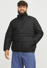 Schwarze gepolsterte Jacke mit hohem Kragen und Frontreißverschluss. Verfügt über ein gestepptes Muster und eine lässige Passform. Ideal für Wärme und Komfort.