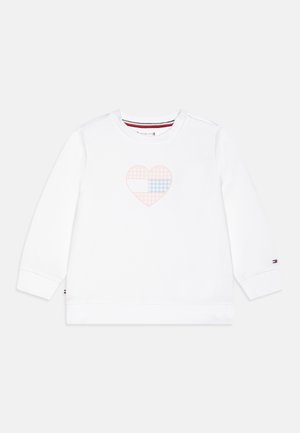 Weißes Langarm-Sweatshirt für Kleinkinder mit einem rosa und blau karierten Herz auf der Brust und kleinem Logo am linken Ärmelbündchen.