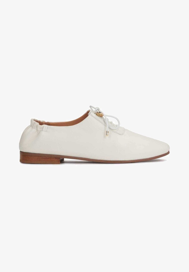 Chaussure plate en cuir blanc avec bout arrondi, dos élastiqué et lacets décoratifs. Semelle en bois avec une hauteur de talon minimale.