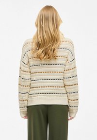 Crème trui met horizontaal gestreept patroon in blauw, bruin en beige. Beschikt over een gebreide textuur en geribbelde manchetten. Gecombineerd met olijfgroene broek.