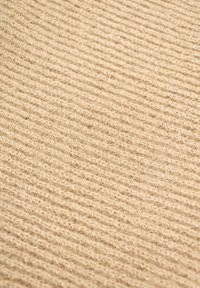 Beige textiel met een ribbelpatroon, gemaakt van zachte vezels waarin subtiele glinsterende draden zijn verwerkt.