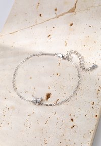 Silver chain bracelet with a butterfly charm featuring clear crystals. The chain has a delicate link design and a lobster clasp with extension.
