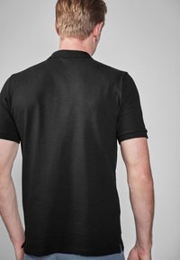 Sort polo shirt lavet af glat bomuld, med en klassisk krave, korte ærmer og sideslids ved sømmen for nem bevægelse.