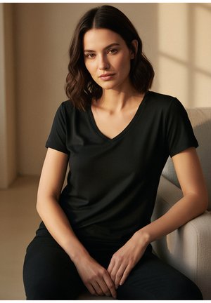 Schwarzes V-Ausschnitt-T-Shirt aus glattem Stoff mit kurzen Ärmeln, weitem Schnitt und minimalistischem Design, kombiniert mit dunkler Hose.