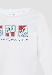Weißes Langarmshirt mit drei bunten Drucken: Palme, Sonne und Strandszene, mit dem Text "FUN'S OUT, FUN'S OUT" darunter.