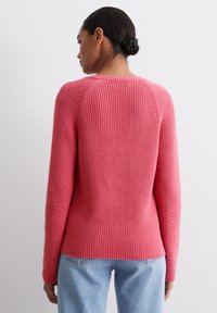 Geribbelde roze gebreide trui met een ronde hals en lange mouwen, voorzien van textuurelementen op de mouwen en een aansluitend ontwerp.