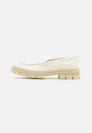 Cremefarbener Slip-On-Loafer mit grober beiger Profilsohle und minimalistischem Design, seitlich auf weißem Hintergrund.