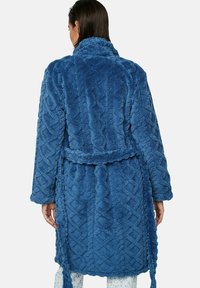 Blauwe textuur robe van een pluizige, zachte stof. Heeft een gevlochten ontwerp, lange mouwen en een strik in de taille. Geen zichtbare hardware.