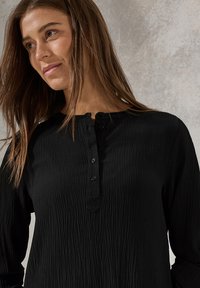Svart, texturerad långärmad skjorta med henley-krage, som har tre knappar fram och en något lös passform.