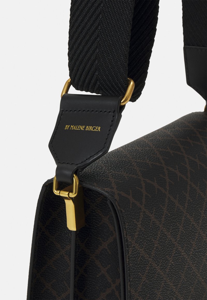 Brun mönstrad handväska med en svart flätad rem. Har guldfärgad hårdvara och en svart läderetikett präglad med "BY MALENE BIRGER."
