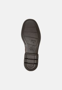 Suela de zapato de goma con superficie texturizada, que presenta crestas para agarre y logotipo en relieve. Color predominantemente marrón oscuro.