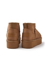 Botas de tobillo de ante marrón con plataforma plana, que presentan un diseño cosido y una etiqueta de Gioseppo en la parte posterior. Acabado texturizado y suave.