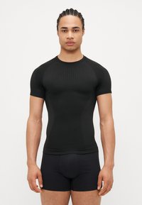 Kurzarm schwarzes Sportshirt aus dehnbarem Material mit glatter Textur. Mit strukturiertem Design auf der Vorderseite, enganliegendem Schnitt.