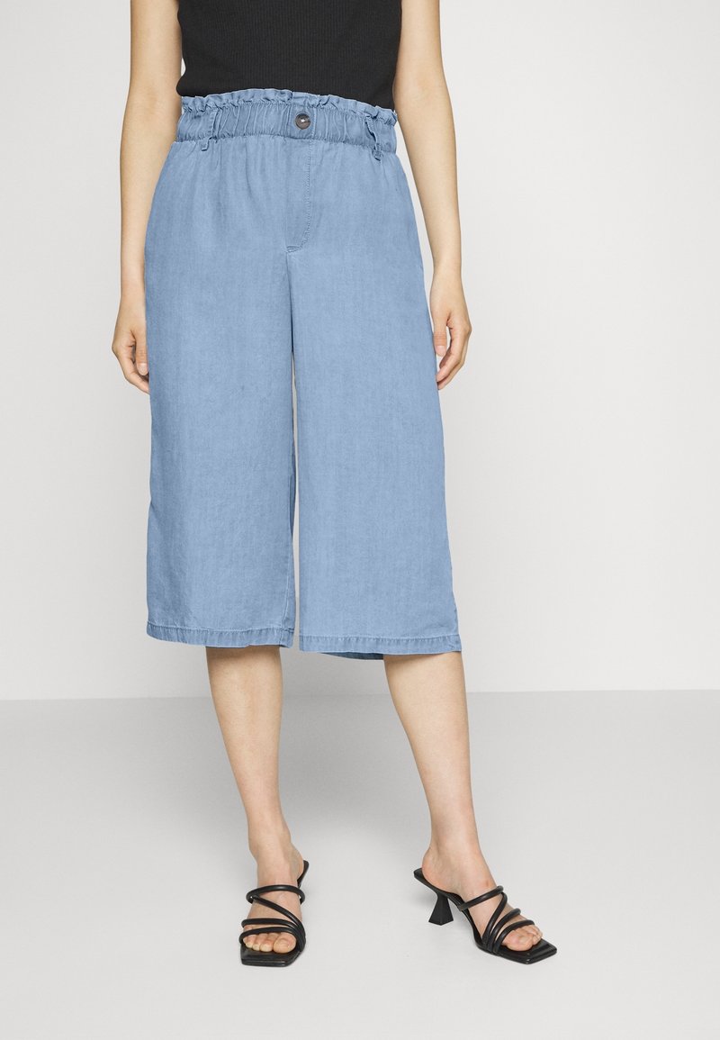 Světle modré široké culottes s elastickým pasem a knoflíkovým detailem. Vyrobené z měkké, texturované tkaniny, s kratší délkou.