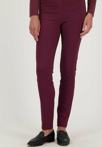 Bordeauxgekleurde fitted pantalons van zacht materiaal, met een normale taille, twee voorzakken en een gladde textuur. Gemaakt in combinatie met zwarte instappers.