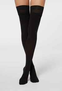 Sorte thigh-high strømper med en gennemsigtig finish, der har et tekstureret fiskenetbånd øverst. Glat tekstur og tætsiddende design.