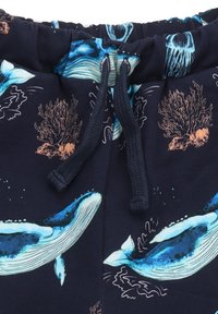 Marineblaue Stoffshorts mit Grafiken von Blauwalen und Korallen, elastischem Bund mit Kordelzug und glatter Textur.