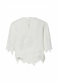 Hvid bluse med albuelange ærmer, florale blonder langs kant og ærmer, nøglehul på ryggen med enkelt knaplukning.