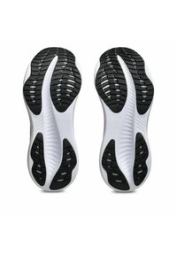 Semelles de chaussures de sport en noir et blanc avec une semelle en caoutchouc texturée, un design courbé et des rainures mises en avant pour une traction et une flexibilité accrues.