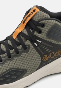Pilkas tinklelis sportinis batelis su juodais raišteliais ir oranžinėmis detalėmis. Yra struktūruoti perpuolimai ir paminkštinta padas komfortui ir palaikymui.