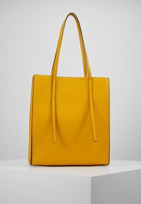 Borsa tote in pelle gialla con due manici lunghi, forma rettangolare, texture liscia e cuciture a contrasto nere.