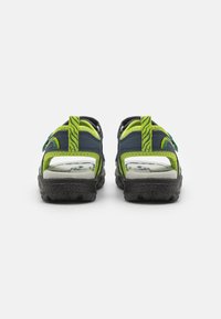 Baksidevisning av sandaler med en navy blå og neongrønn fargekombinasjon, justerbare stropper og strukturerte svarte gummisåler for godt grep.